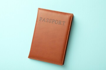 Passport in brown cover on light blue background, top view