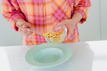 Charming mature woman in casual style preparing a nutritious breakfast at home interior, daylight