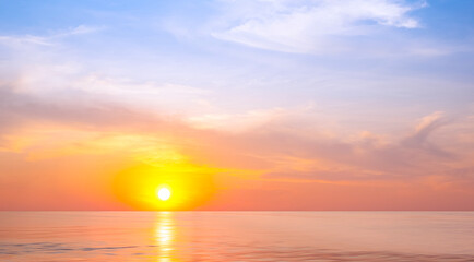Golden sunrise sky background over sea in the morning with clouds and beautiful orange sunlight reflection on water surface. Idyllic summer sunset seascape view