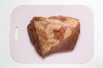 Top view of a piece of marinated meat on a plastic cutting board.