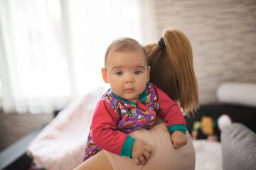Fototapeta premium Caring mother holding newborn baby girl at home