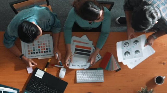 Top view of smart people throw paper and giving high five at meeting table with financial document and stock market analysis paper scattering around. Aerial view of team celebrate project. Symposium.