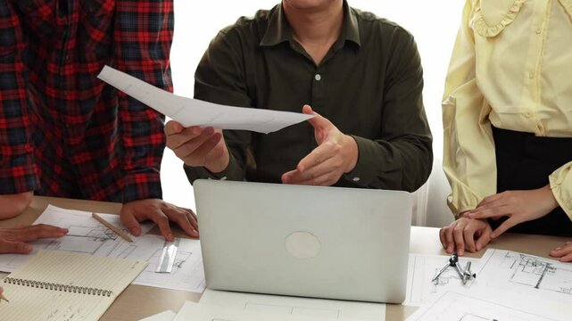 Smart architect and safety engineer discussion about building plan on table with architectural document, measurement tools and wooden block scatter around at modern office. Closeup. Delineation.