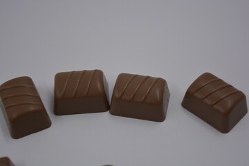 Food, food, very tasty milk candies are located on white plastic. Chocolates are made in the form of leaves, walnuts, medallions, round and square shapes.