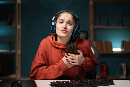 E-sport female gamer play video game at home using pc. Brunette woman gaming player looking camera thank you with all my heart hands on chest express sincere gratitude