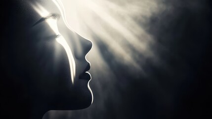 Fototapeta premium A silhouette of a person's profile illuminated by soft beams of light, creating a dramatic and ethereal atmosphere.