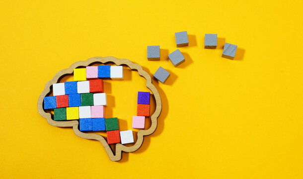 Brain made of colorful blocks breaking into gray pieces. Mental health challenges and cognitive decline.