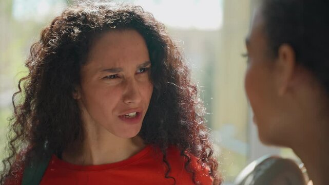 Two multiracial women girls females Hispanic Latina students arguing angry talking conflict problem discuss emotional frustrated argument quarrel in university school college study education trouble