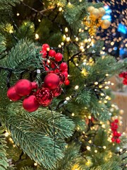 A close-up of a beautifully decorated Christmas tree with warm white string lights, red berries, and golden ornaments. 