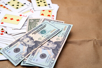 Fototapeta na wymiar A pile of dollars and a deck of poker cards spread out on a table