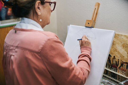 Elderly woman drawing on canvas in her studio