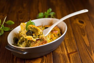cauliflower and brussels sprouts casserole with cheese, in a ceramic dish on a wooden table