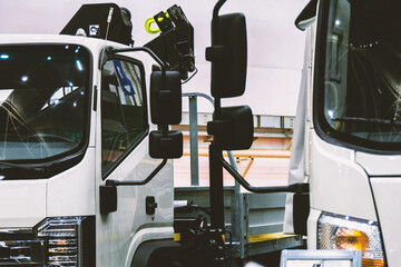 Two medium-duty white trucks. The vehicles are photographed in close-up, allowing for a detailed...