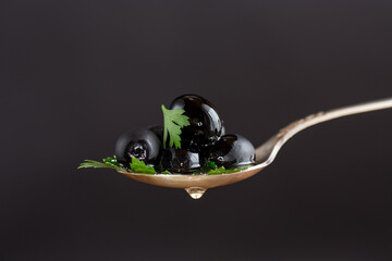 black olives in a spoon isolated on a black background