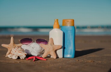 Beach essentials on sandy shore with sunscreen, starfish, and sunglasses