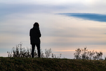 the silhouette of a tourist on the hill during sunset
