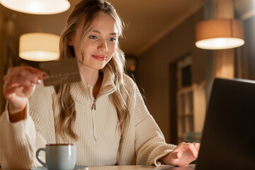 Young woman with credit card shopping online in coffee shop or cafe. Shopping online