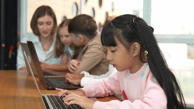Group of multiethnic children working or playing laptop, programing system. Happy funny diverse student working by using laptop to writing prompt or programing system. Smart classroom. Erudition.