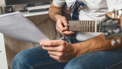 Young man learning play electric guitar at home