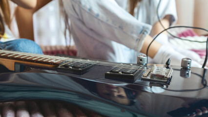 Little girl singing with microphone at home, concentrating, other child girl playing guitar. Close up
