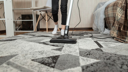 Low section of girl cleaning floor with vacuum cleaner at home