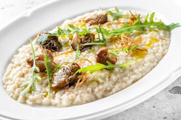 A delicious serving of creamy risotto topped with sautéed mushrooms and fresh arugula, drizzled with olive oil. Perfect for food lovers and gourmet presentations.
