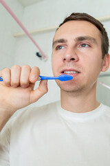 Young man brushing teeth with toothbrush at home in the bathroom