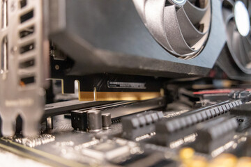 close-up of a graphics card installed on a motherboard, showcasing gold connector pins and cooling fans for high-performance computing