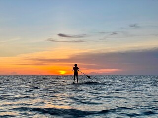Silhouette of a man on a stand up paddle board at sunset in the Gulf of Mexico on St. Pete Beach,...