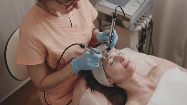 Aesthetician performing a specialized facial treatment on a relaxed woman at a beauty spa. The concept of wellness, skincare, and pampering is captured in a serene, professional setting.