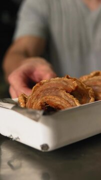 Closeup vertical slowmotion footage of a man putting a plate of fried chicharrones on a table