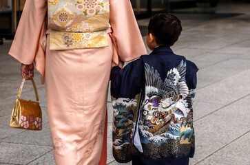 Mother and son dressed in traditional Japanese costume holding hands