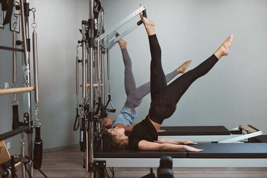 Young women exercising in a gym on pilates machines.