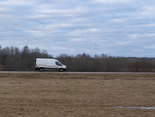 White modern delivery shipments cargo courier van is driving between trees. Business distribution and logistics express service.