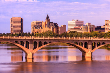 A bridge spans a river with a city skyline in the background