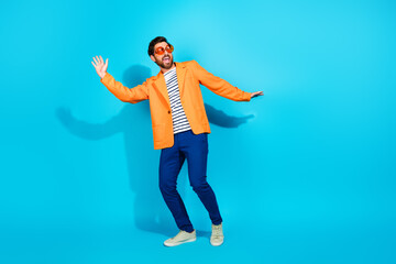 Cheerful man in orange jacket expresses joy in front of a vibrant turquoise background.