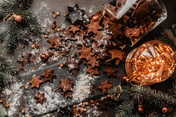 A rustic holiday setting featuring a jar of homemade cookies, surrounded by cinnamon sticks and festive lights. Pine branches add a cozy, warm atmosphere perfect for the winter season.