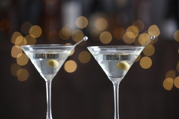 Martini cocktail with olives in glasses on blurred background, closeup. Bokeh effect