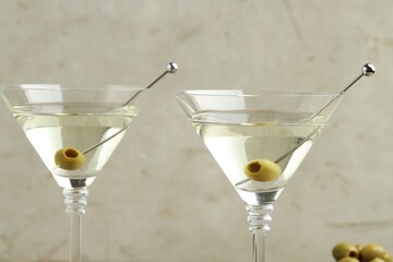 Martini cocktail with olives in glasses on light background, closeup