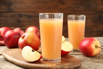 Tasty apple juice in glasses and fresh fruits on wooden table, closeup