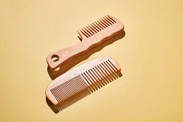Two wooden combs on a yellow background.