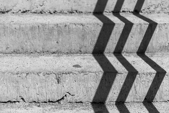 Rough gray concrete stairs with stripes of shadows, background photo.