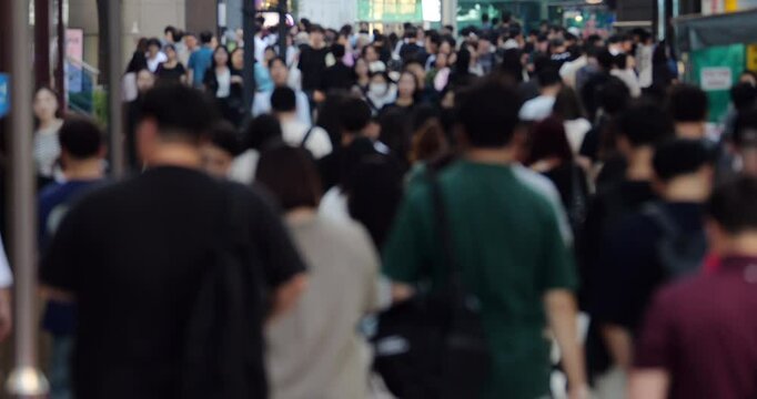 Blurred slow-motion view of crowd of people during rush hour in Gangnam, Seoul. Office workers and commuters fill street pavement, symbolizing daily home-to-work routine of modern Korea.
