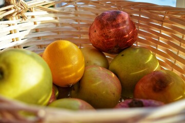 Close up photo sun rays on a wicker basket with apples pomegranates and oranges view from inside...