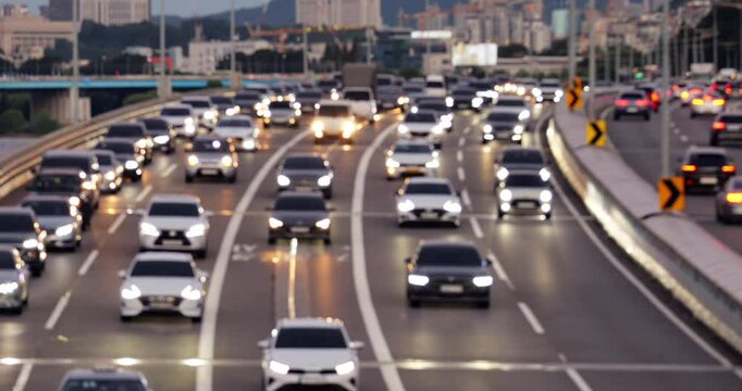 Rather busy traffic on Olympic-daero in evening, defocused view of urban traffic. Outermost lane is almost stationary, cars formed long queue. On other lanes, there is movement, and road nearly empty