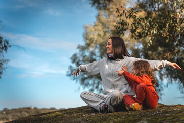 A woman and a child are sitting on a hillside, enjoying the outdoors