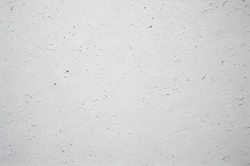 White concrete wall exhibiting rough textured surface with cracks