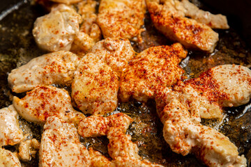 chicken fillet fried in spices crispy crust in a frying pan
