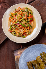 Couscous with vegetables, udon noodles with meat in spices and dolma on a wooden table