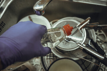 A gloved hand pours detergent. Dishwashing liquid.